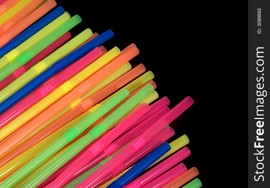 Colorful straws, angled in from the bottom left corner of the photo, stand out dramatically against the black background.