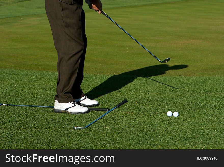 Golfer taking practice swings and aligning on a golf course. Golfer taking practice swings and aligning on a golf course