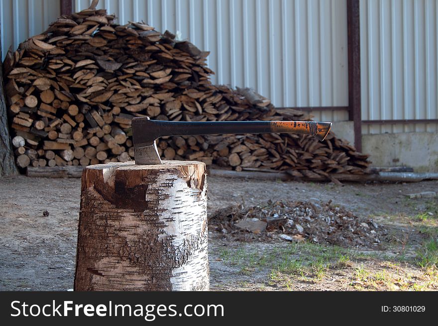 Axe in stump on the background of firewood. Axe in stump on the background of firewood