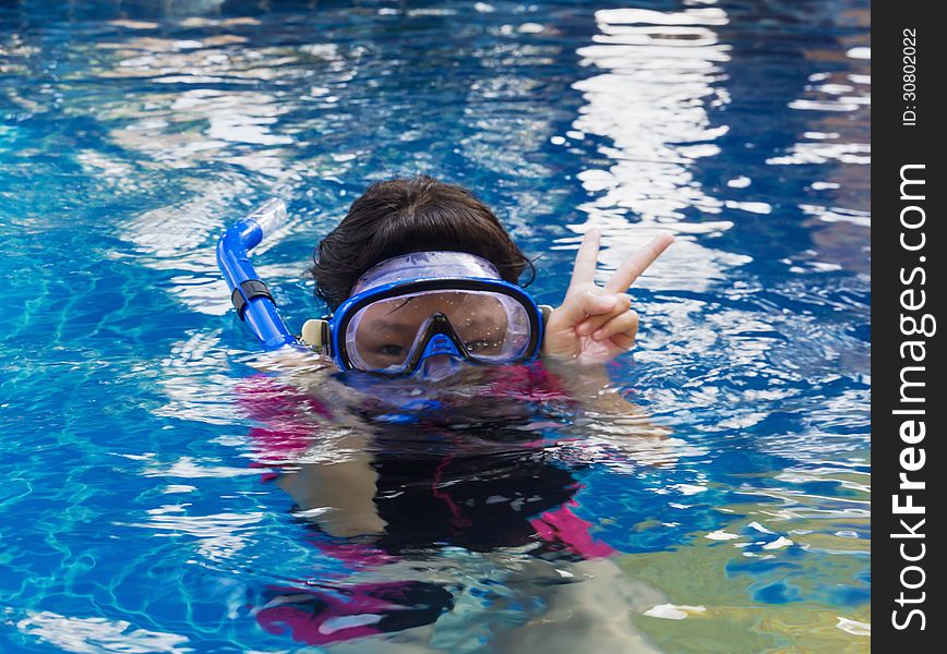 Girl relaxing on the side of a swimming pool wearing goggles and snorkel. Girl relaxing on the side of a swimming pool wearing goggles and snorkel