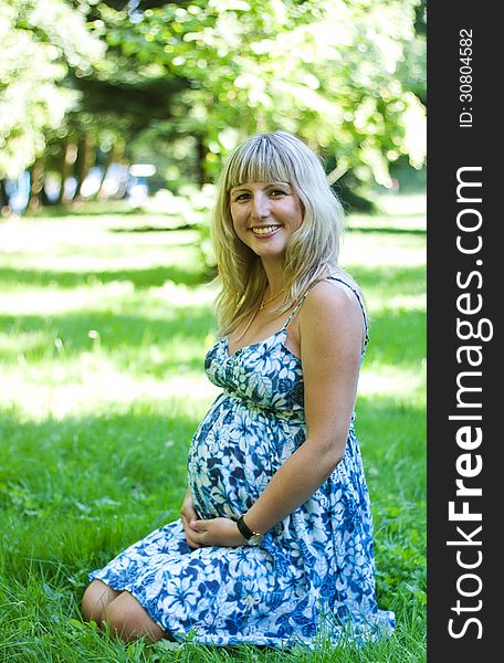 Young pregnant woman in city park onsummer day