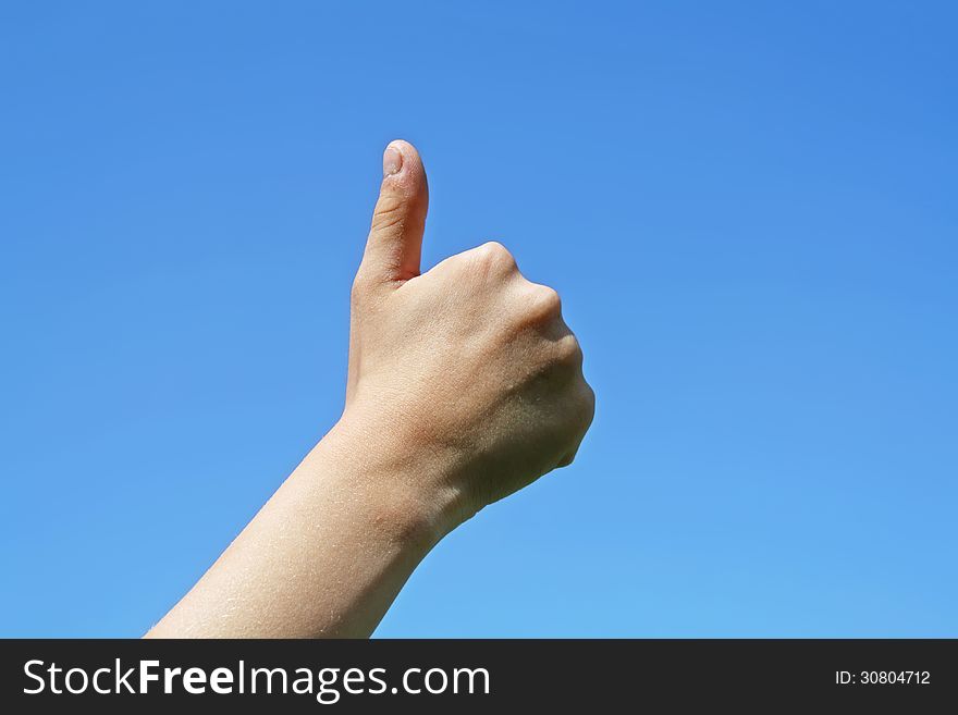 A close-up of a sign of thumb up on a blue sky background. A close-up of a sign of thumb up on a blue sky background.