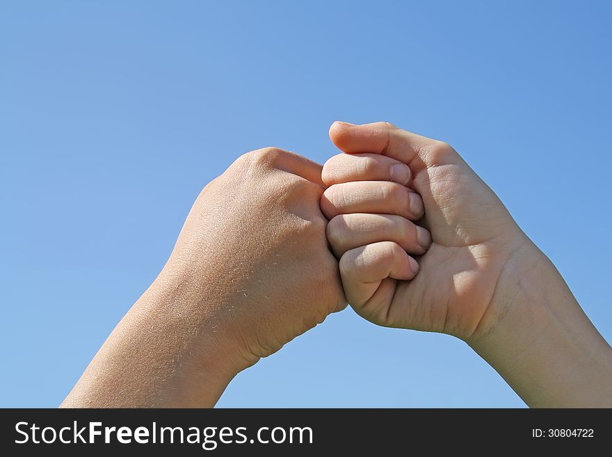 A children's hands on a blue sky background. A children's hands on a blue sky background.