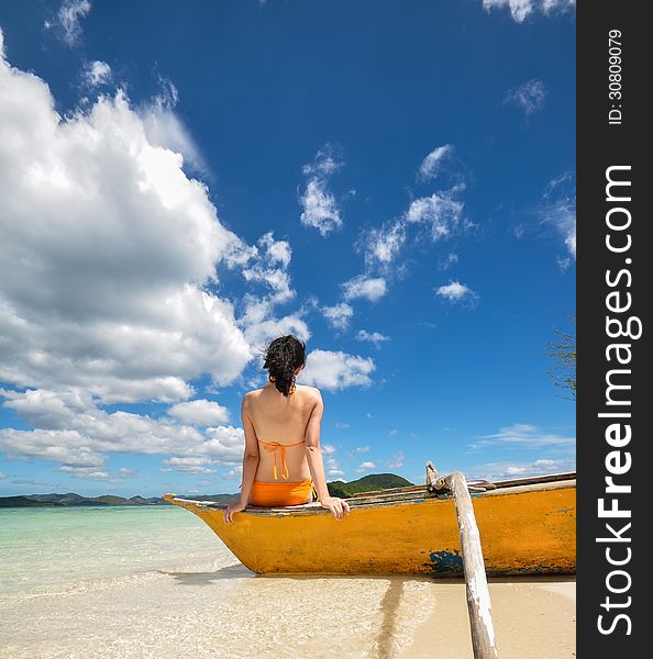 Young girl sit on boat on white beach