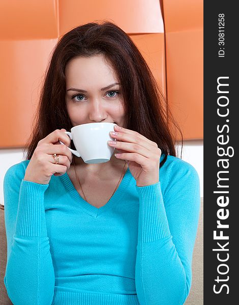 Young woman with a Cup of tea sitting on the couch