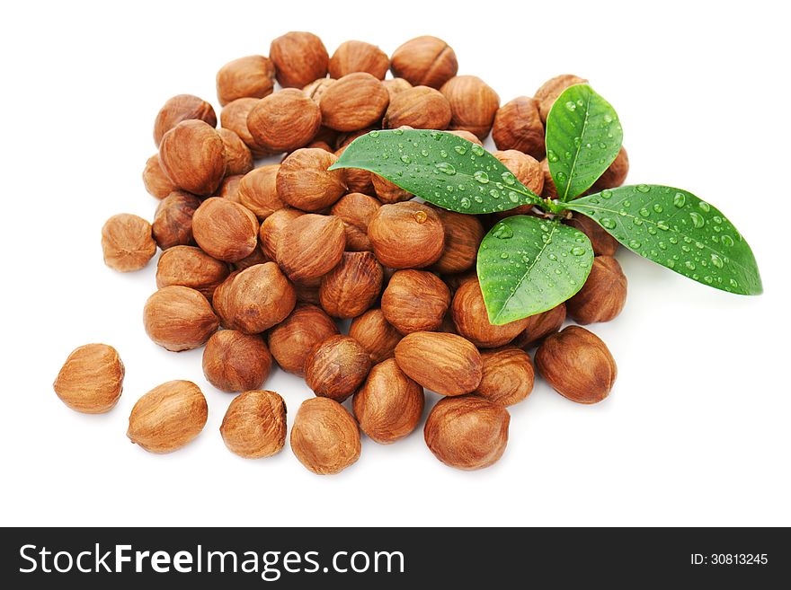 Heap of fresh shelled hazelnuts with green leaves.