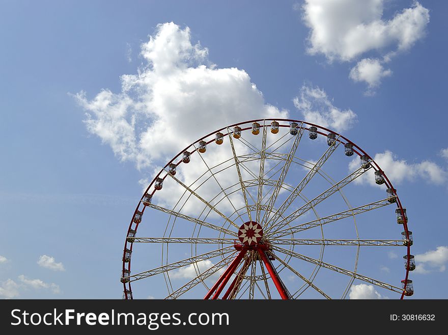 Ferris wheel on the background of sky with clouds
