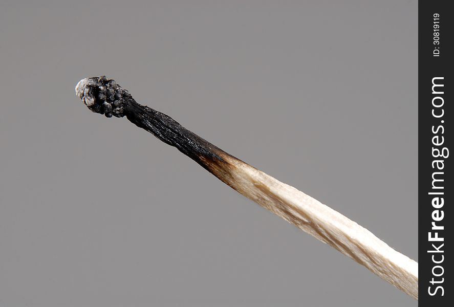 Burnt match on a grey background. Burnt match on a grey background