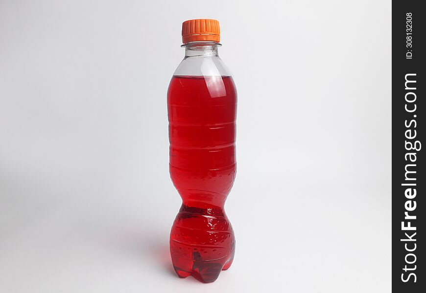 A Bottle Containing A Red Soda Drink And A White Background