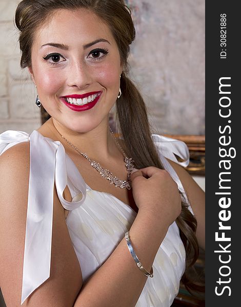 Young attractive woman wearing a necklace, bracelet and a satin bridal designer gown. Young attractive woman wearing a necklace, bracelet and a satin bridal designer gown