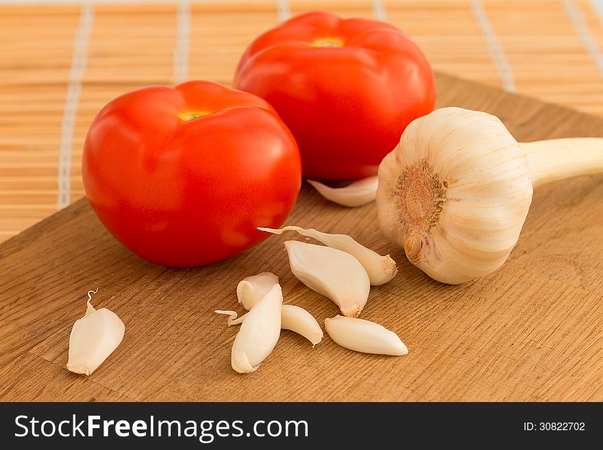 A few cloves of garlic with tomato on wooden table