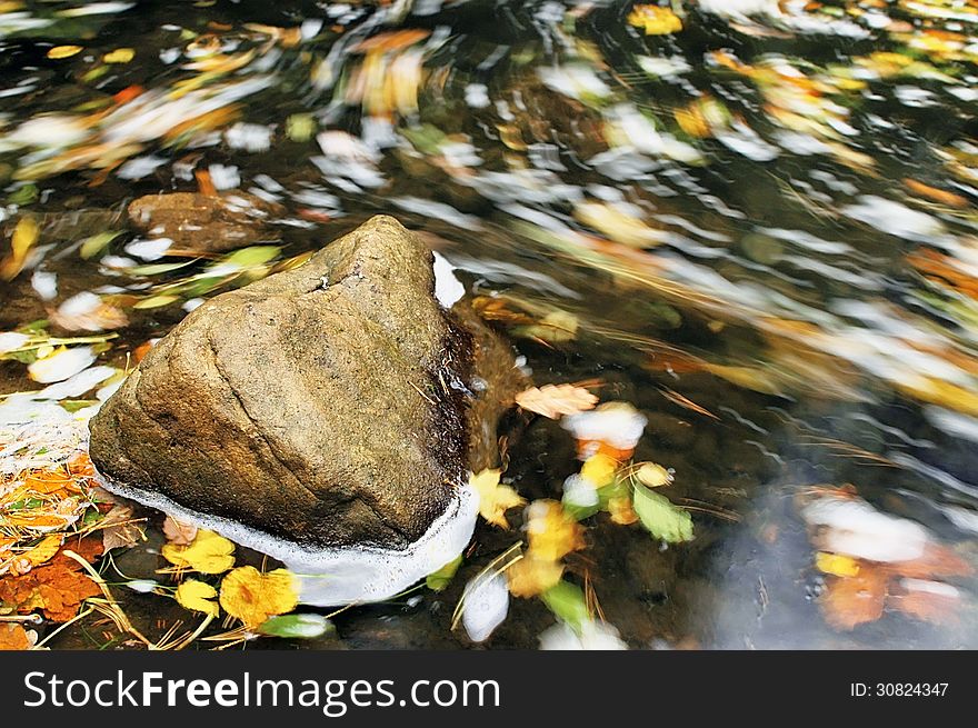 Lone stone in the creek generated by moving leaves. Lone stone in the creek generated by moving leaves