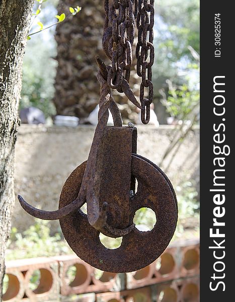 Old rusty pulley of the well, hanging with the chain. Old rusty pulley of the well, hanging with the chain.