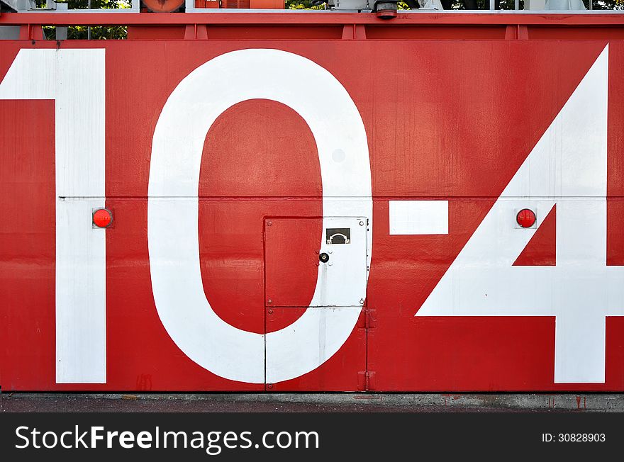 A red japanese tsunami watertight door in osaka bay area with the number 10-4 painted on it. A red japanese tsunami watertight door in osaka bay area with the number 10-4 painted on it