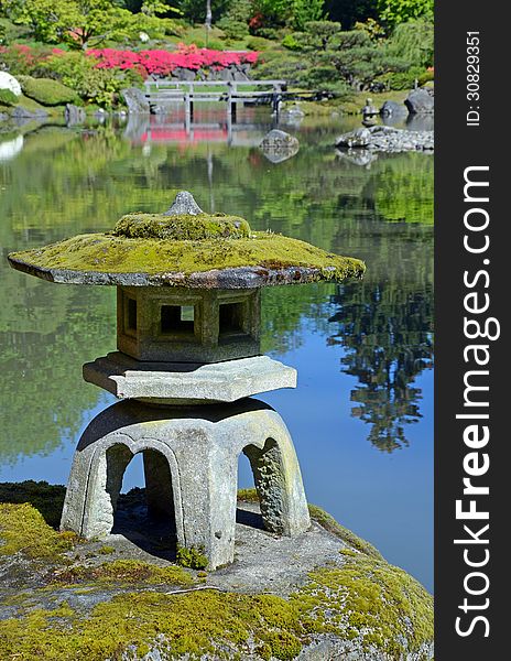 Rock lantern on rock in reflective pond in japanese botanical garden. Rock lantern on rock in reflective pond in japanese botanical garden