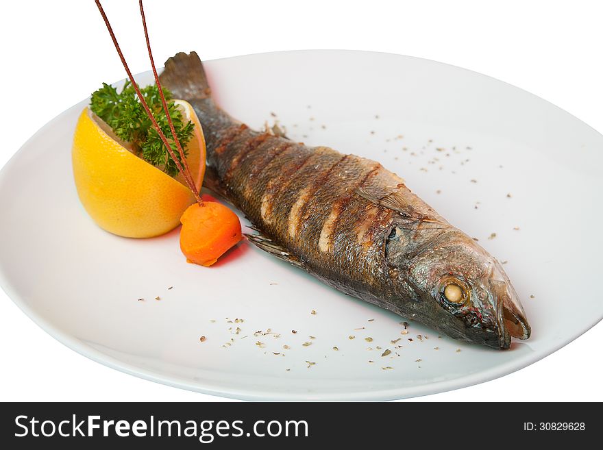 Fried fish decorated with lemon, carrots and vegetables