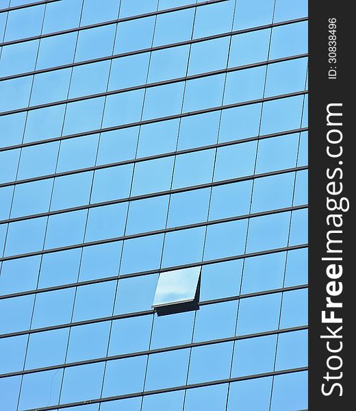 One open window glass in blue glass panel of building. One open window glass in blue glass panel of building