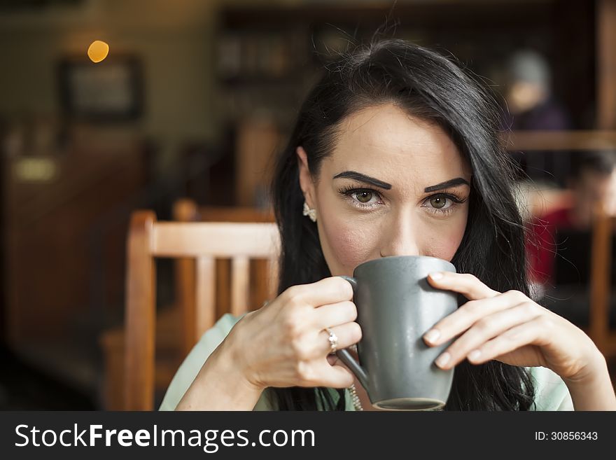 Beautiful young woman with dark brown hair and eyes holding a gray coffee cup. Beautiful young woman with dark brown hair and eyes holding a gray coffee cup.