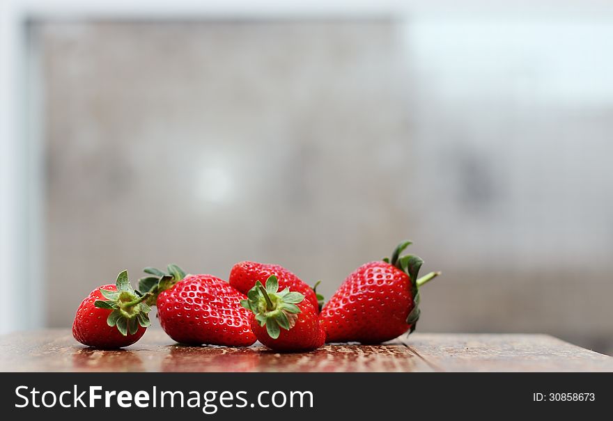 Fresh strawberries on wooden vintage table near the window