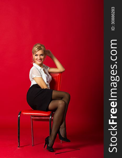 Young woman in a white blouse and black skirt posing sitting in studio