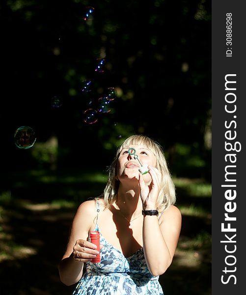 Young pregnant woman blowing soap bubbles outdoor