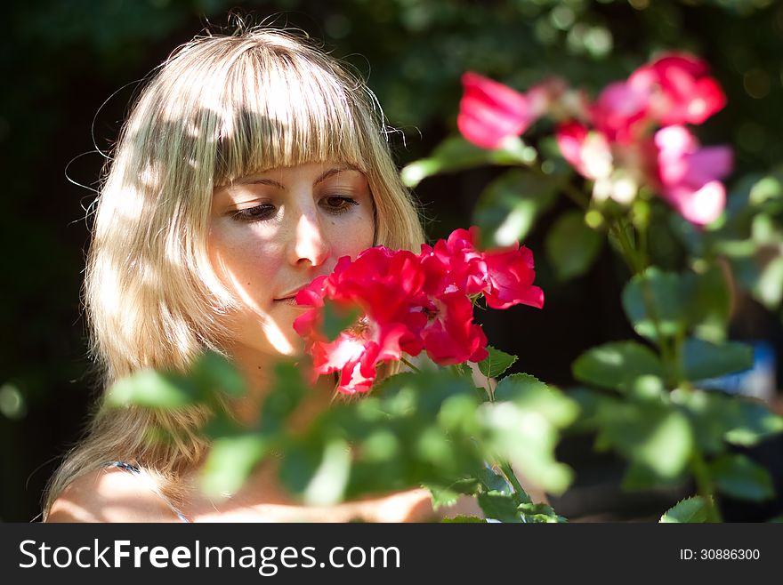 Young woman with red flowers on a walk on summer day