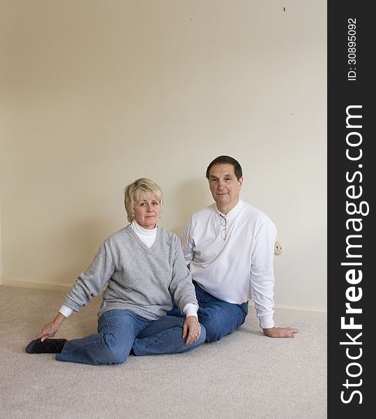 Middle aged couple sitting on the floor of the house they raised their children in, just before moving out. Middle aged couple sitting on the floor of the house they raised their children in, just before moving out.
