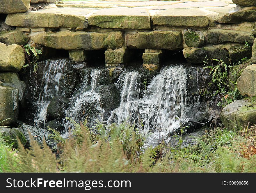 A Pleasant Waterfall Running Under a Stone Paved Path. A Pleasant Waterfall Running Under a Stone Paved Path.