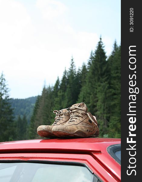 Mountain shoes on a red car with mountains in background