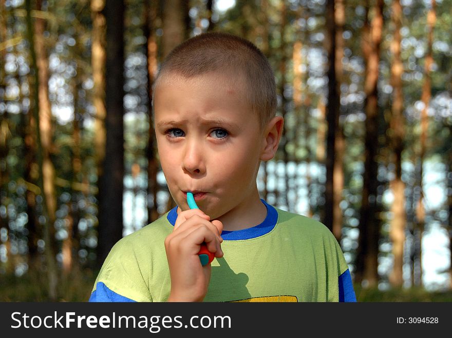 Nearly 5 years young boy is brushing his teeth in forest