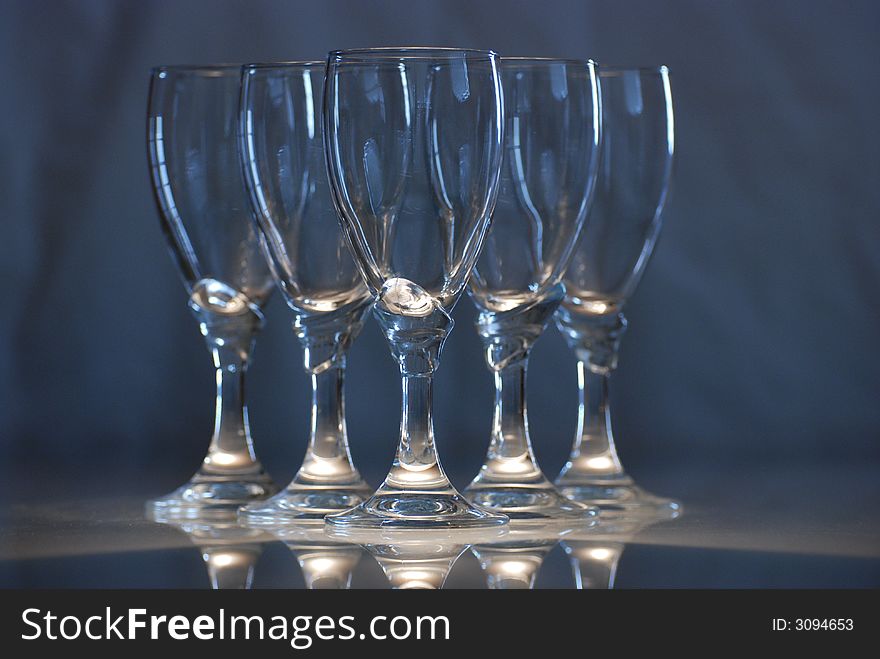 There are five glasses on a glass table.