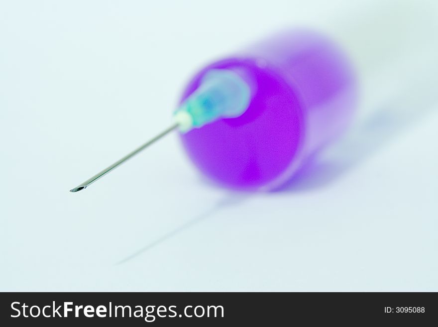 Disposable syringe with needle on it filled with violet liquid against the white background. Disposable syringe with needle on it filled with violet liquid against the white background