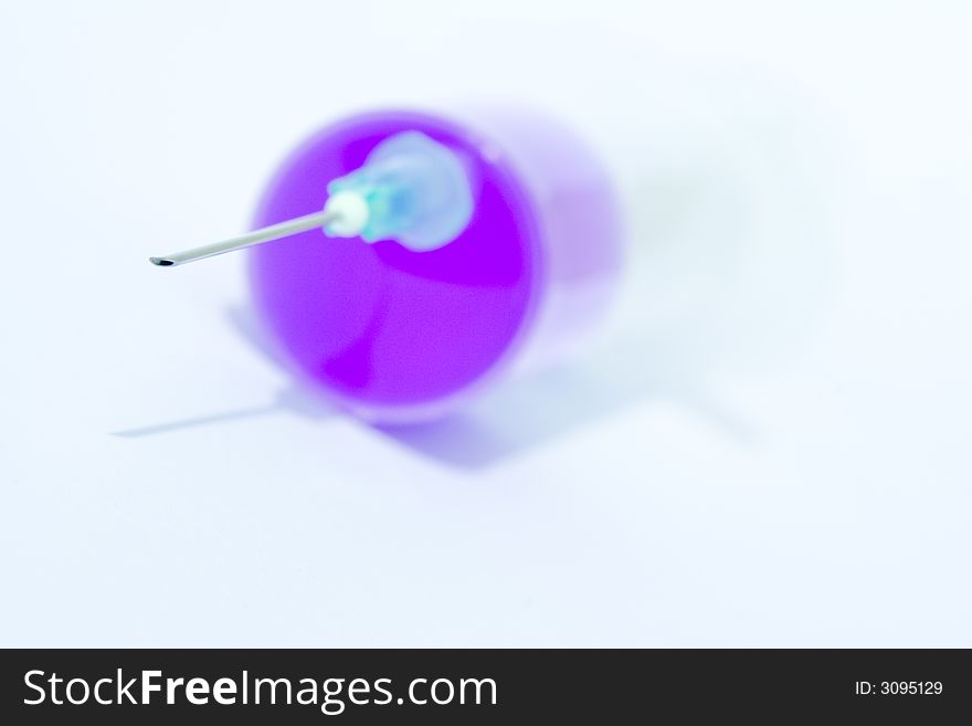 Disposable syringe with needle on it filled with violet liquid against the white background. Disposable syringe with needle on it filled with violet liquid against the white background