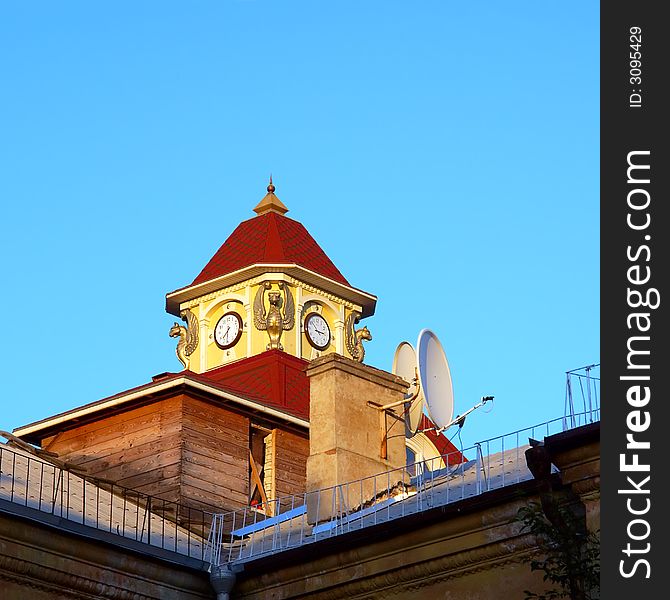 Old and modern - clock tower behind satellite dish in sunset light. Shot in Ukraine.