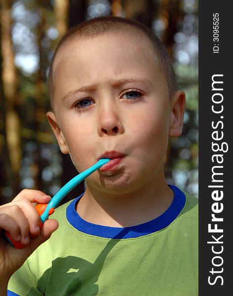 Nearly 5 years young boy is brushing his teeth in forest