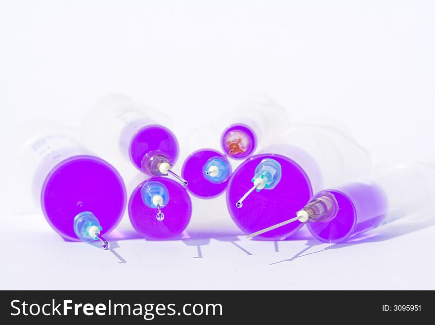 Six different size disposable syringes filled with purple fluid with needles against the white background. Six different size disposable syringes filled with purple fluid with needles against the white background