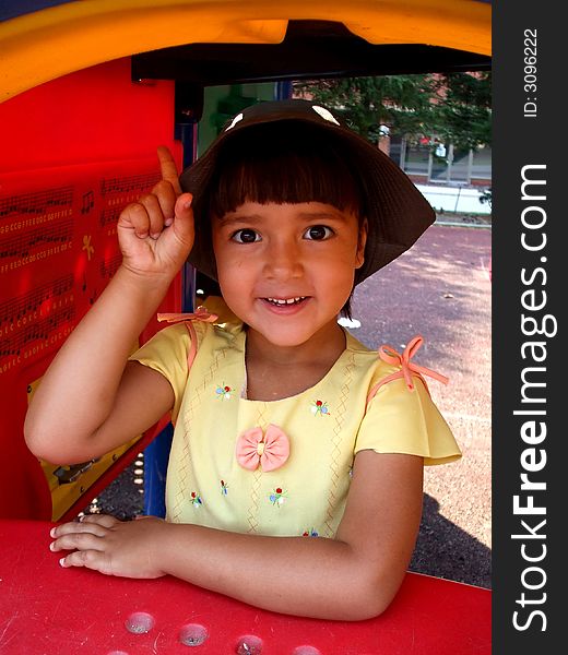 Young pretty girl on the playground. She is pointing her finger up. Young pretty girl on the playground. She is pointing her finger up.