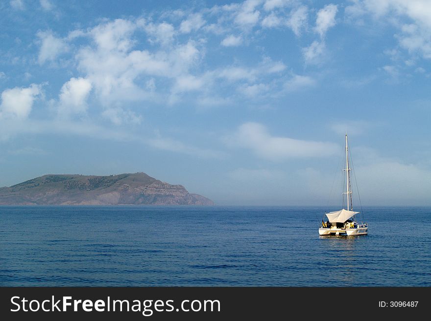 Yacht in the sea on a background of seashore and clouds. Yacht in the sea on a background of seashore and clouds