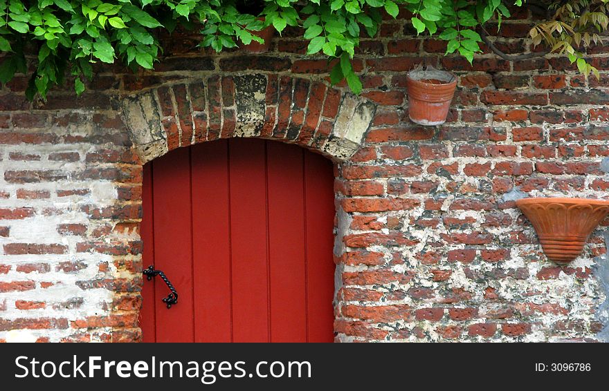 Detail of a old building showing part of a red door and brick wall. Detail of a old building showing part of a red door and brick wall