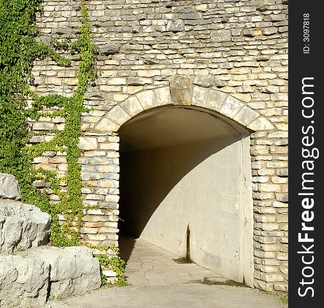 Stone entrance to tunnel walkway with ivy growing up the wall