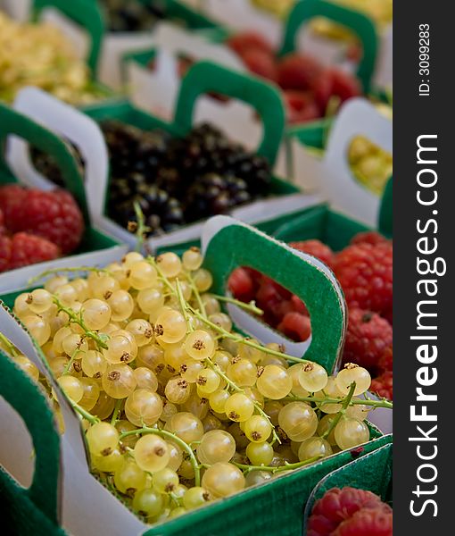 Delicious selection of fresh berries - white currants, raspberries, blackberries - in paper trays on a market display. Delicious selection of fresh berries - white currants, raspberries, blackberries - in paper trays on a market display