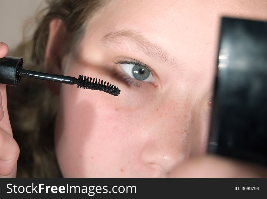 Young woman is putting up some mascara. Young woman is putting up some mascara