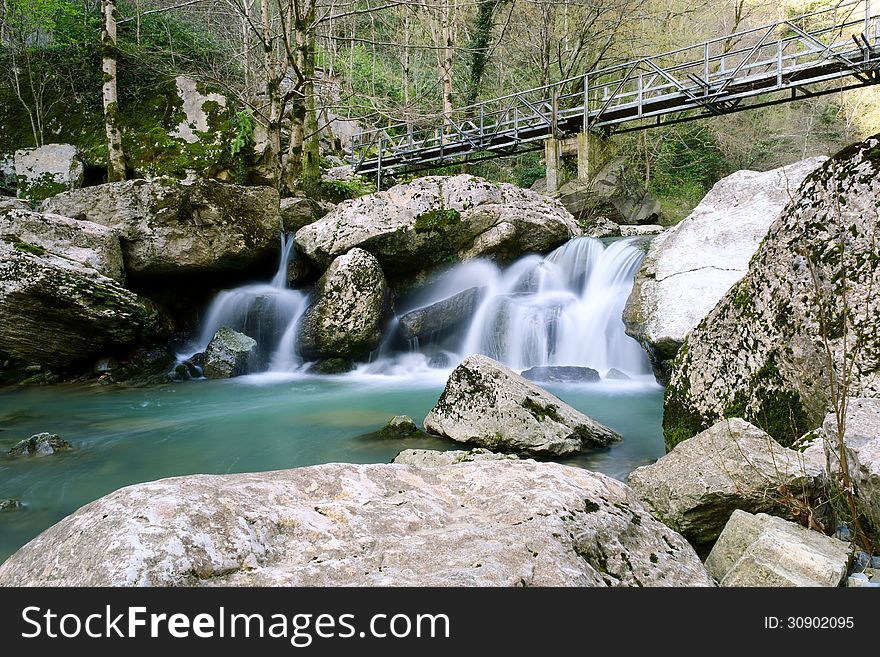 Bridge over the rapid flow of a mountain stream. Bridge over the rapid flow of a mountain stream