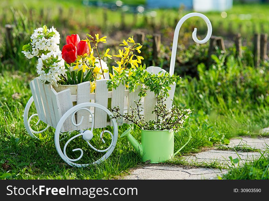 Decorative wheelbarrow and watering can with bright flowers. Decorative wheelbarrow and watering can with bright flowers