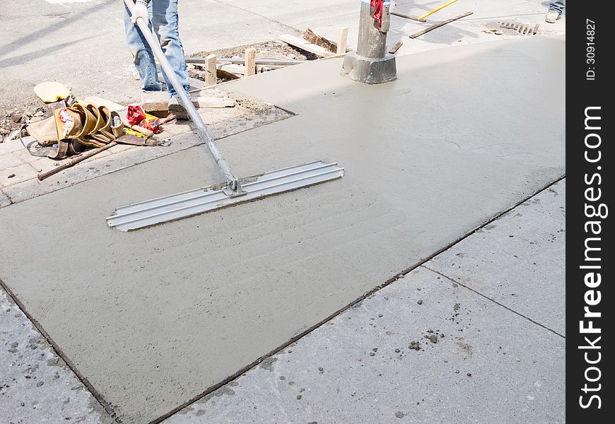 Laying down new sidewalk in urban setting. Laying down new sidewalk in urban setting