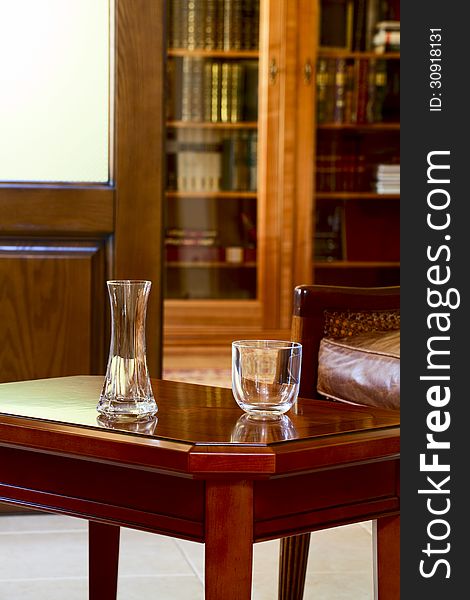 Vase and a glass on the coffee table against the background of cupboard with books