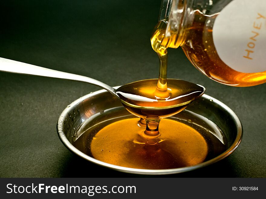 Honey being poured out on spoon.