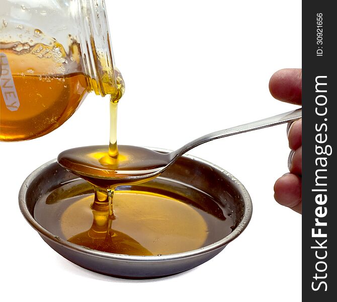 Honey being poured out on spoon, isolated on white background with clipping path.