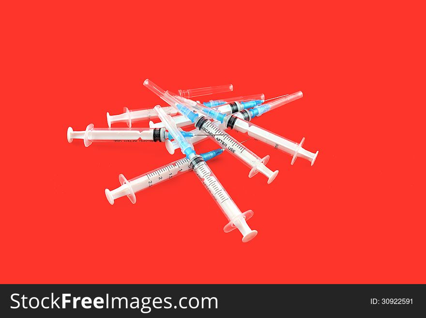 Used syringes are scattered against a red background