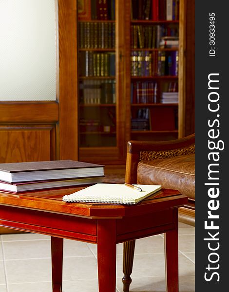 Coffee table with notebook and books on the background of the bookcase. Coffee table with notebook and books on the background of the bookcase